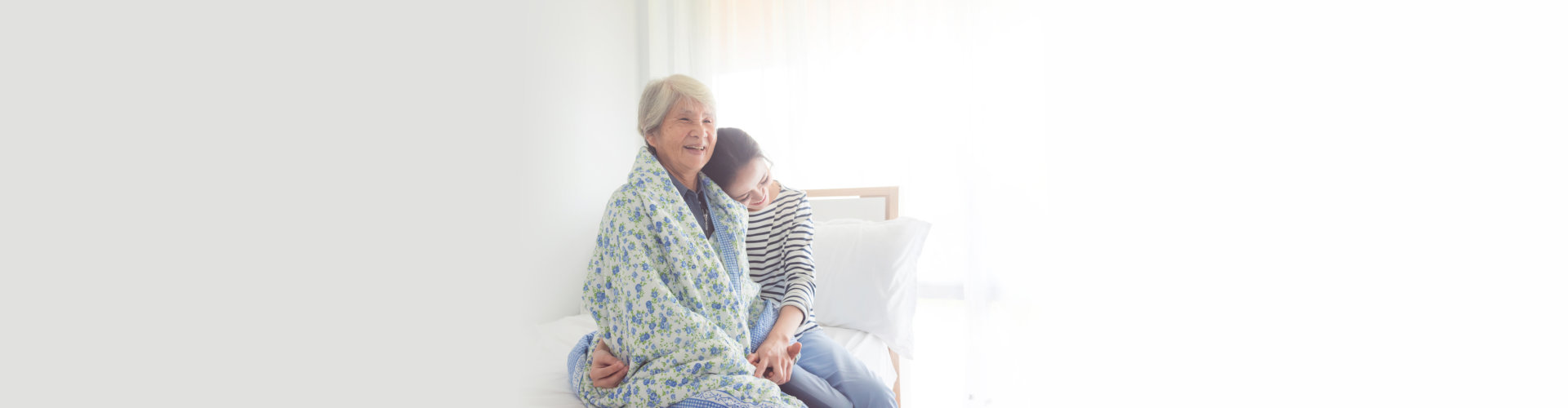 caregiver embracing an elderly woman